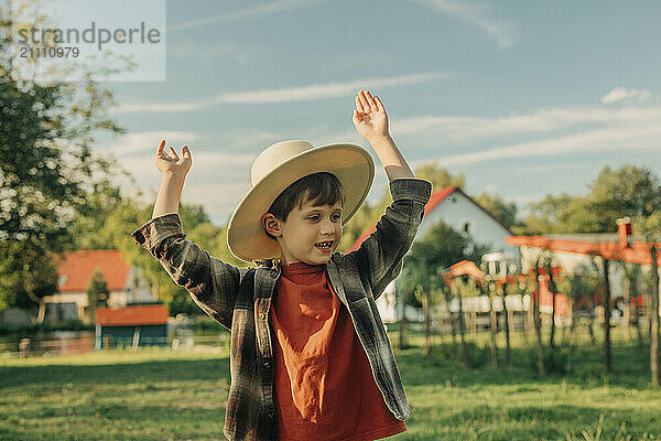 Playful boy with arms raised in farm