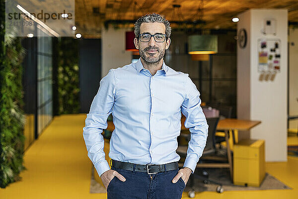 Businessman standing with hands in pocket at co working space