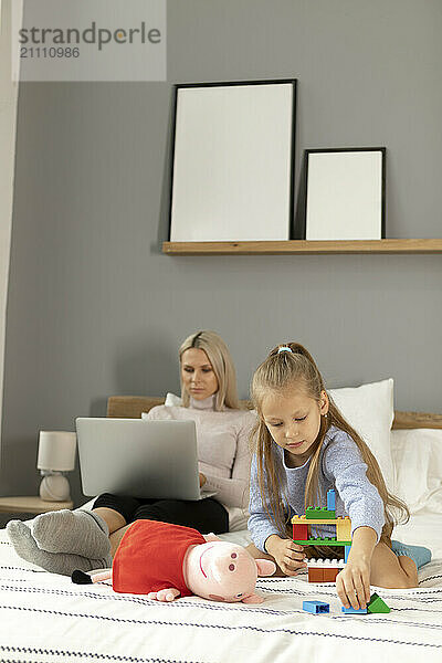 Girl playing with toys near mother at home