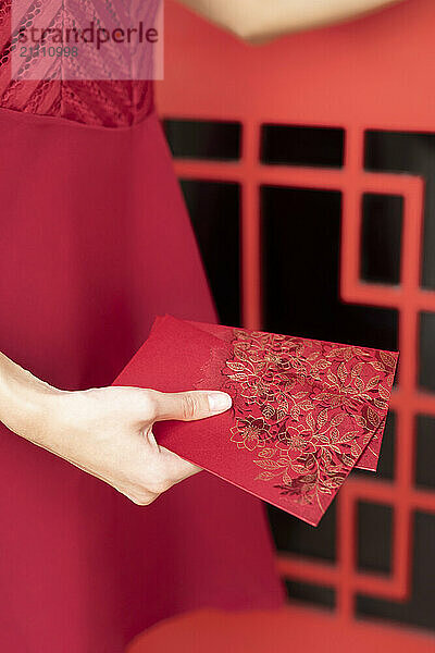 Hand of woman holding red envelope near door