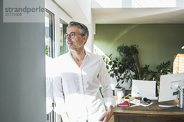 Businessman looking out of window in home office