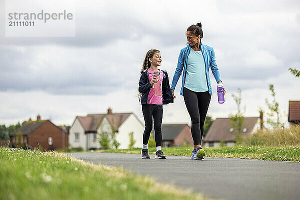 Mother and daughter walking together on footpath