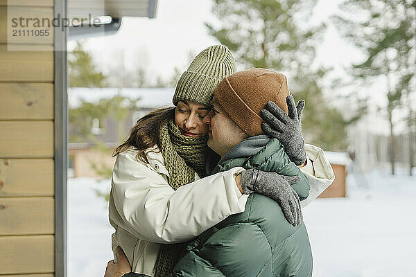 Woman in warm clothes embracing man