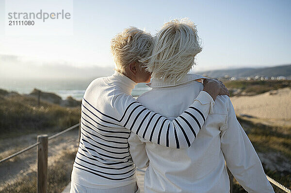 Mother embracing daughter walking towards beach