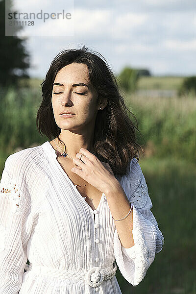 Beautiful woman with eyes closed standing in meadow