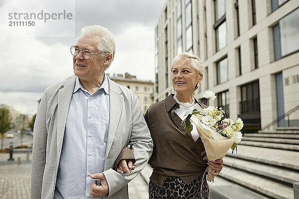 Happy man and woman walking arm in arm at street