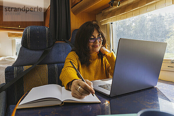 Smiling senior woman freelancer working on laptop in motor home