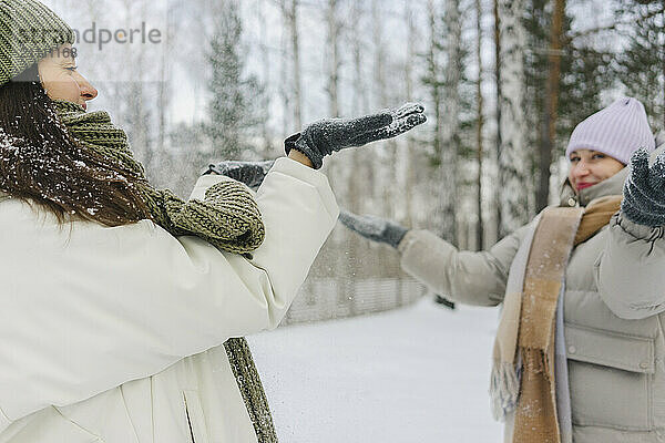 Playful friends throwing snow in winter