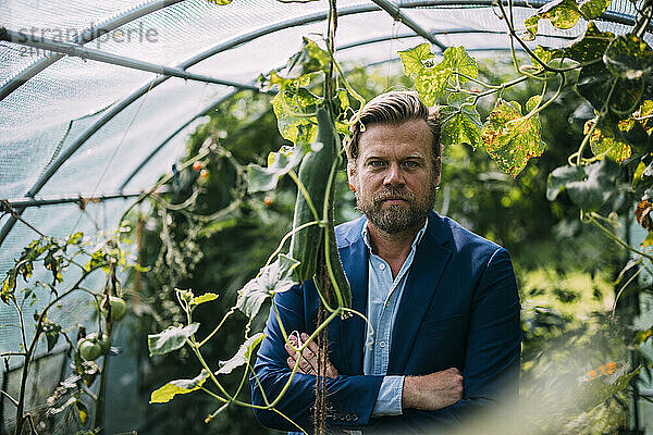 Businessman wearing blazer with arms crossed at greenhouse