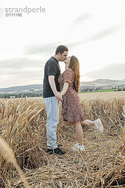 Young couple kissing amidst agricultural field