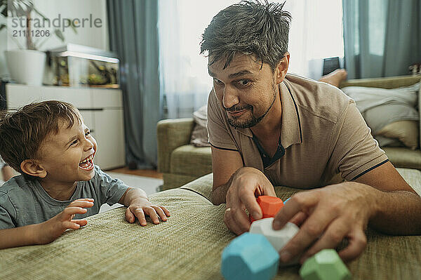 Happy boy playing with father on sofa at home