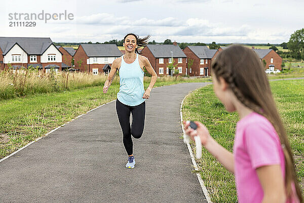 Daughter timing mother running on footpath