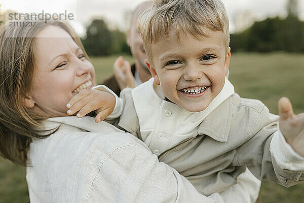 Cheerful boy spending leisure time with mother at park