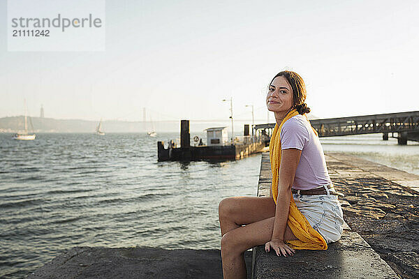 Smiling young woman sitting on promenade