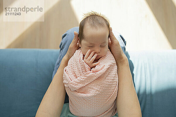 Hands of mother holding baby wrapped in blanket