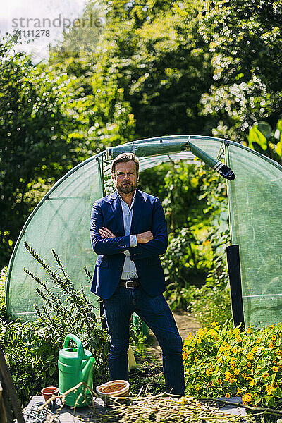 Agronomist standing with arms crossed near greenhouse