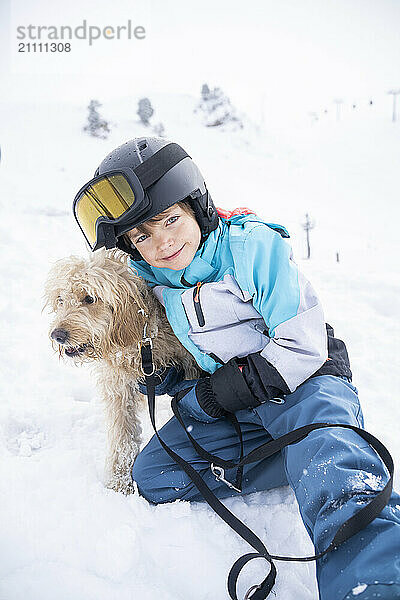 Happy boy with doodle dog on snow in winter