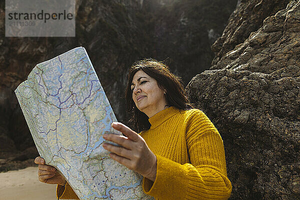 Senior woman with map searching for direction on beach