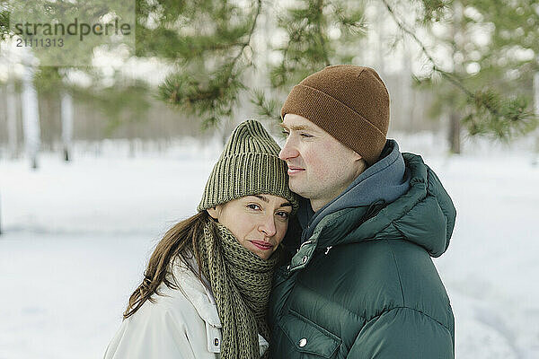 Woman leaning on man standing on snow in winter