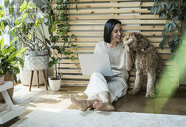 Happy woman working and feeding dog at home