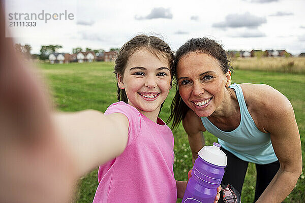 Smiling girl taking selfie with mother in lawn