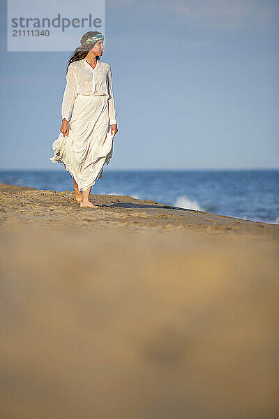 Young woman in white dress standing at seashore