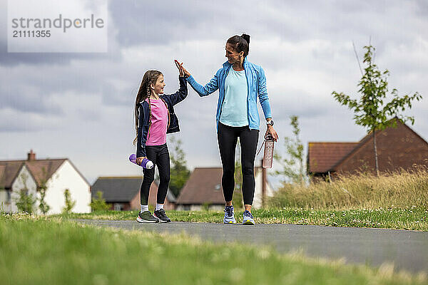 Mother and daughter giving high-five walking on road