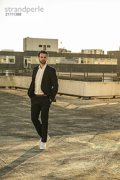 Thoughtful businessman standing on terrace at sunset