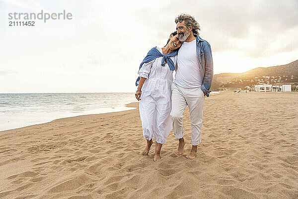 Heterosexual couple standing on sand by sea