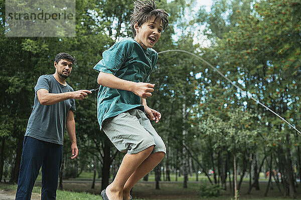 Father and son playing with jumping rope at park