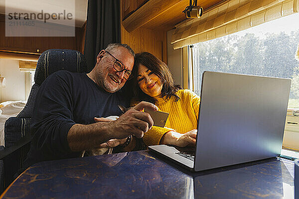 Happy senior couple doing online shopping in motor home