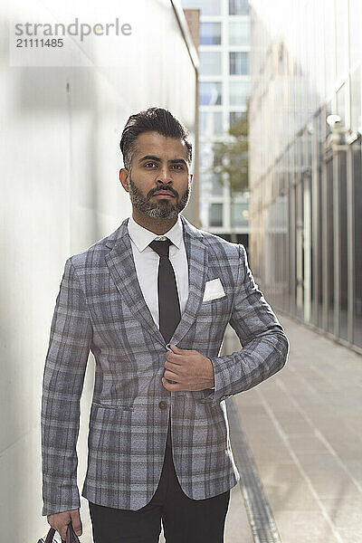 Businessman in suit standing near wall outside building