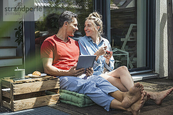 Couple relaxing on balcony with digital tablet