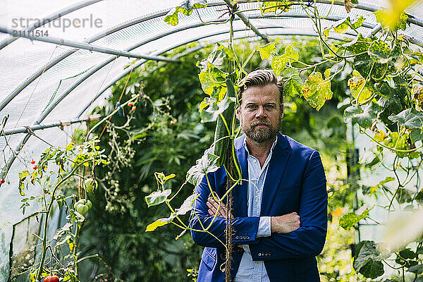 Businessman standing with arms crossed in greenhouse