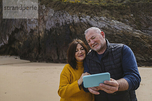 Elderly couple using smart phone at beach