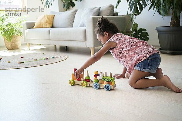 Girl playing with toy vehicle near sofa at home