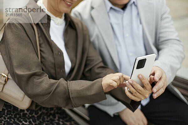 Hands of couple using smart phone in street