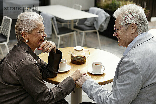 Affectionate couple holding hands on table at cafe