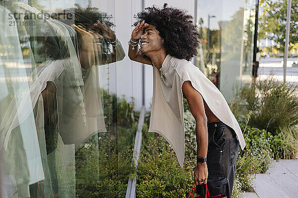 Smiling gay man looking through glass window of store