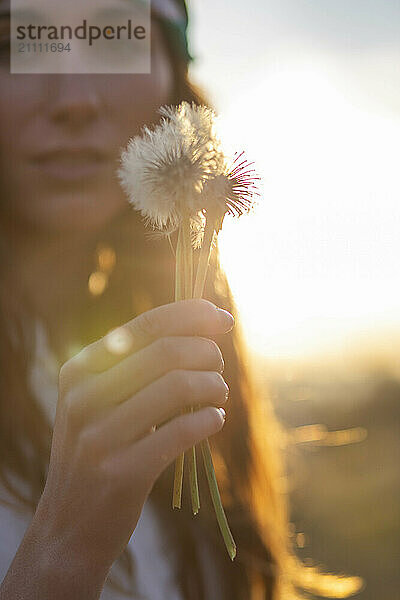 Beautiful woman holding dandelion flower