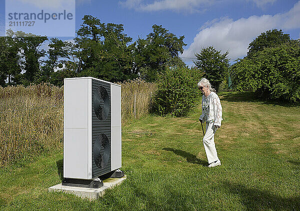 Senior woman near heat pump in meadow