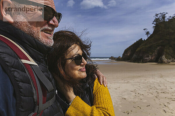 Senior woman in sunglasses leaning on man at beach