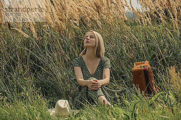 Blond hair woman sitting amidst reeds on sunny day