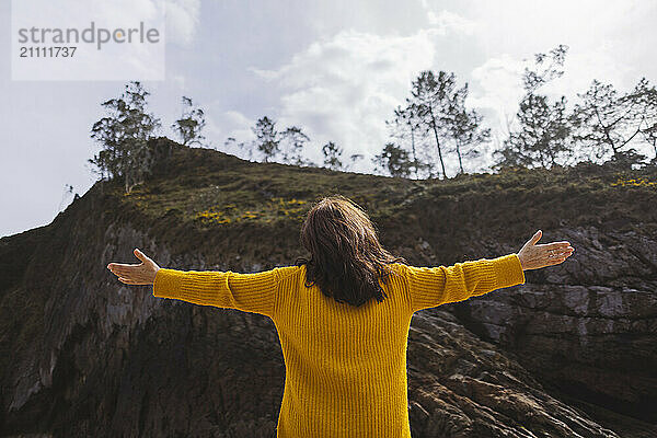 Carefree woman with arms outstretched in front of mountain