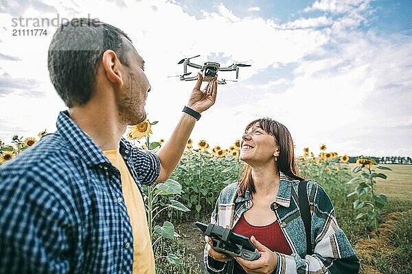 Happy couple flying drone at sunflower field