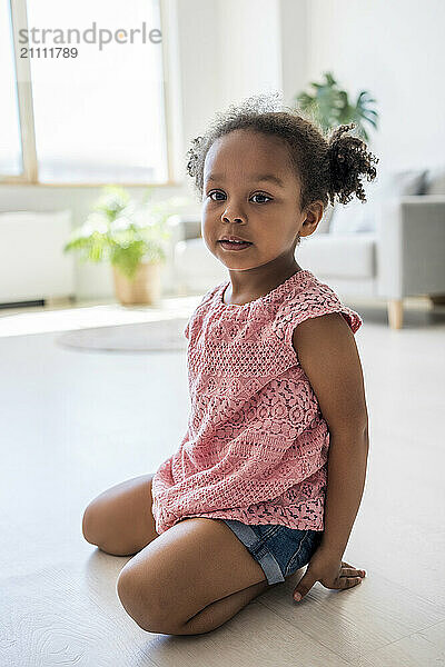 Girl with pigtails sitting on floor at home