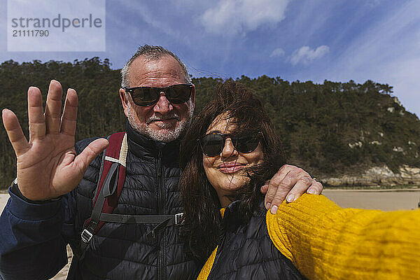 Senior couple wearing sunglasses taking selfie at beach