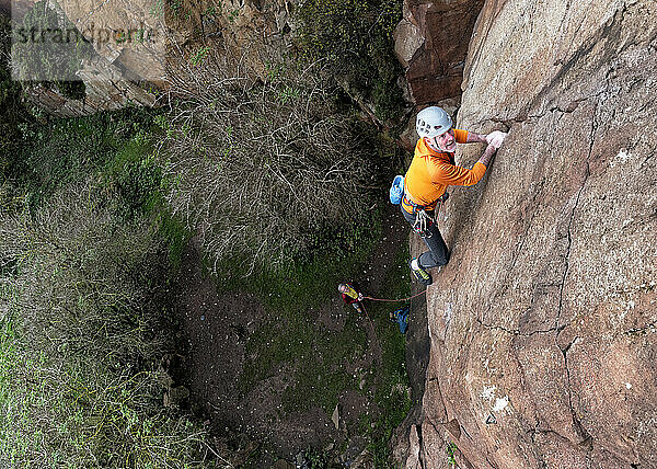 Determined climber climbing on rock mountain in North Berwick Law