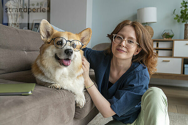 Young woman and Welsh Corgi dog with eyeglasses at home