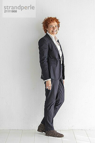 Redhead businesswoman standing in front of white wall